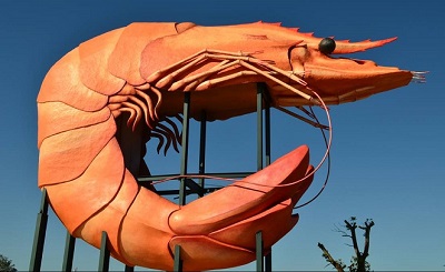 The Big Prawn, a giant orange prawn sculpture on a frame against a blue sky
