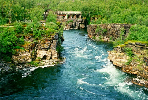 A fast-flowing river running through a rocky gorge, crossed by a bridge